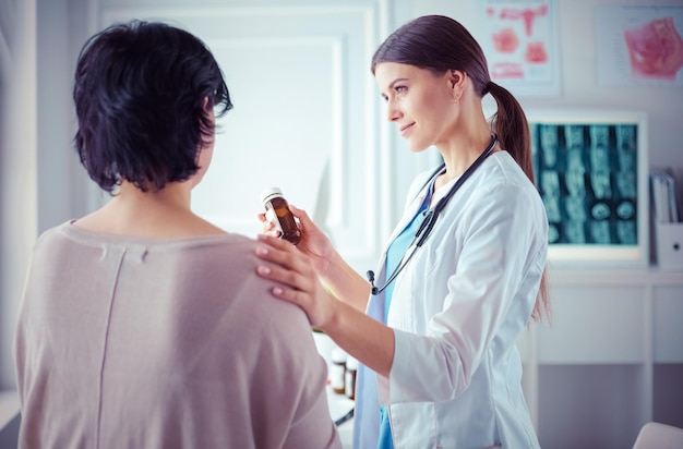 Beautiful female doctor explaining medical treatment to a patient holding a bottle of medicaments