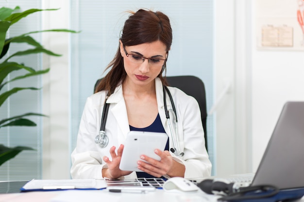 Beautiful female doctor in her studio using a digital tablet