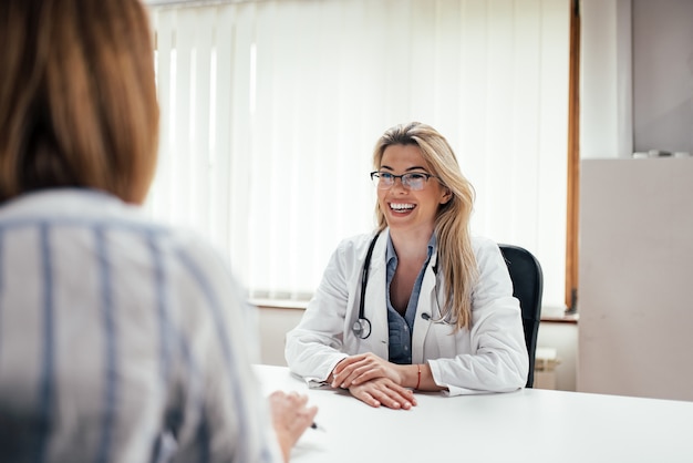 Beautiful female doctor laughing while talking to a patient.