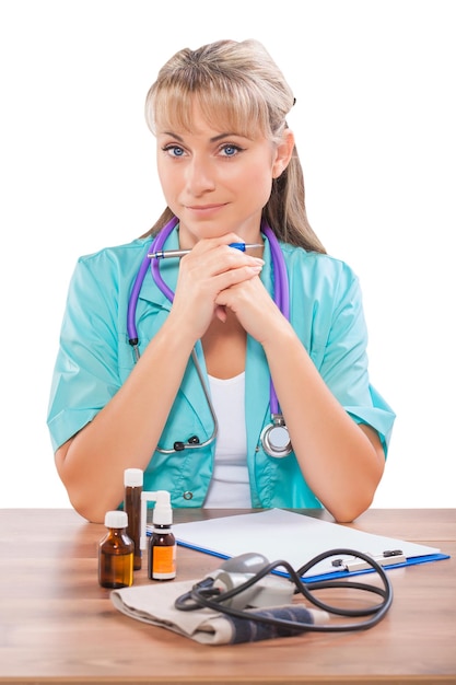 Beautiful female doctor sitting at table and looking at camera