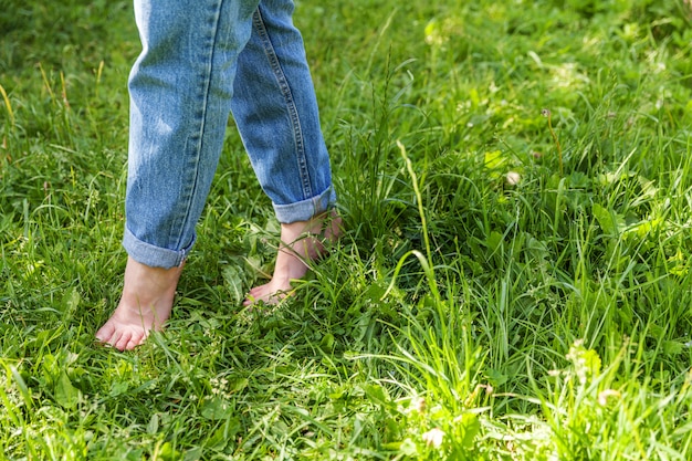 beautiful female feet walking on grass in sunny summer morning