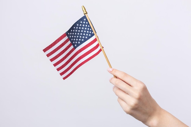 A beautiful female hand holds an American flag on a white background