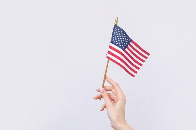 A beautiful female hand holds an American flag on a white background