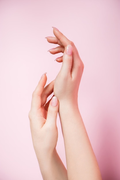 Beautiful female hands on a pink background. Spa and body care concept. Image for advertising.