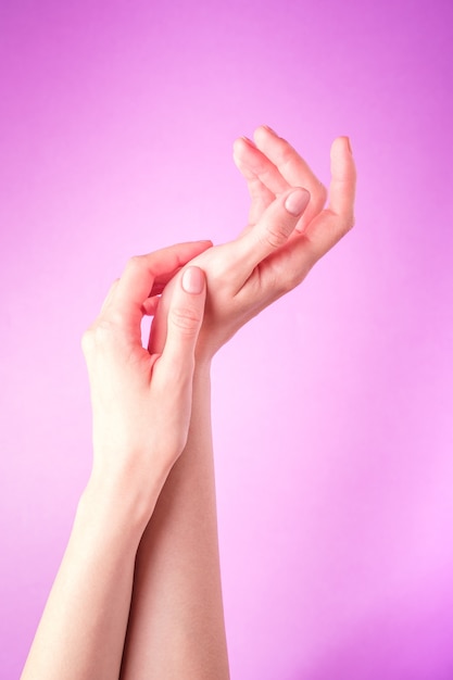 Beautiful female hands showing fresh cute manicure, skin and nail care concept, purple wall