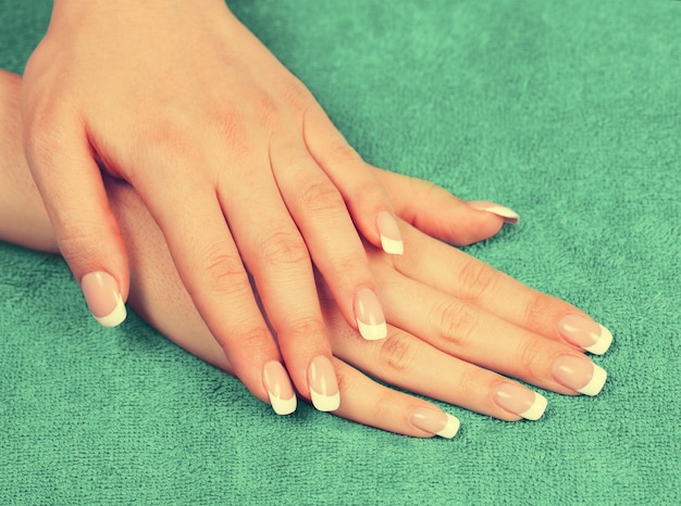 Beautiful female hands with french manicure on green towel