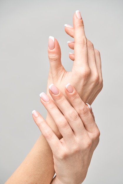 Beautiful Female Hands with French manicure over light grey surface