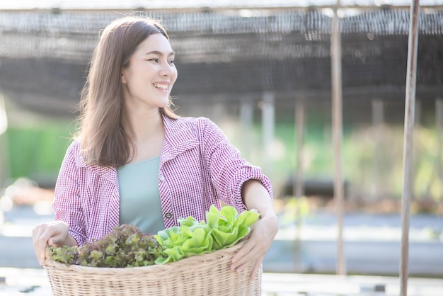 Beautiful female holds fresh vegetables produce from the rooftop greenhouse garden and planning organic farm