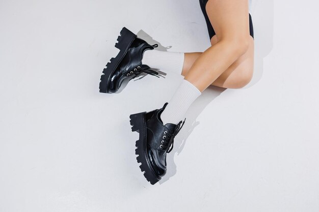 Beautiful female legs in leather black boots on a white background Copy space