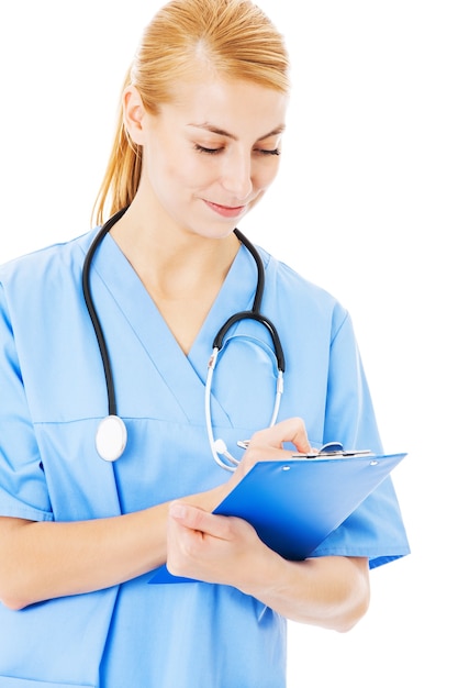 Beautiful female nurse writing on clipboard isolated over white background