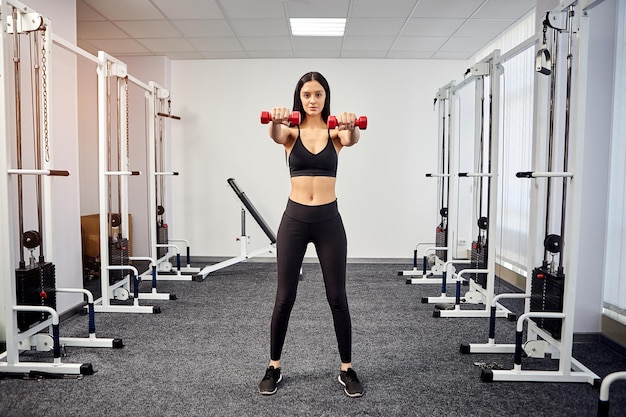 Beautiful Female patient trains in rehabilitation kinesio clinic using dumbbells