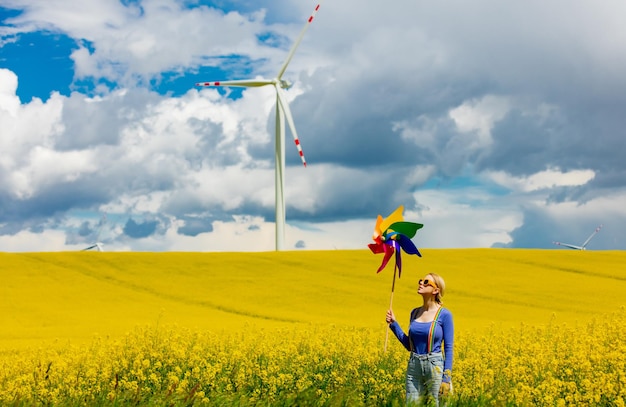 Beautiful female in rainbow LGBT suspenders for pants and pinwheel in rapeseed field