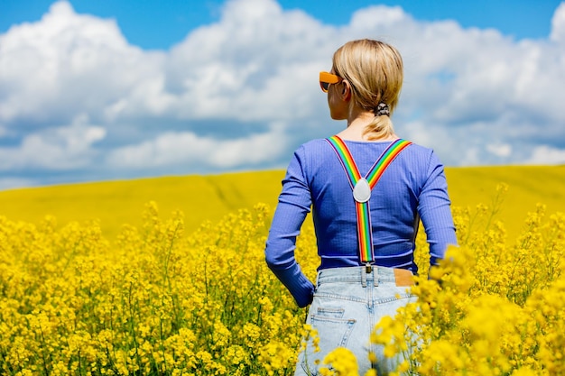 Beautiful female in rainbow LGBT suspenders for pants in rapeseed field