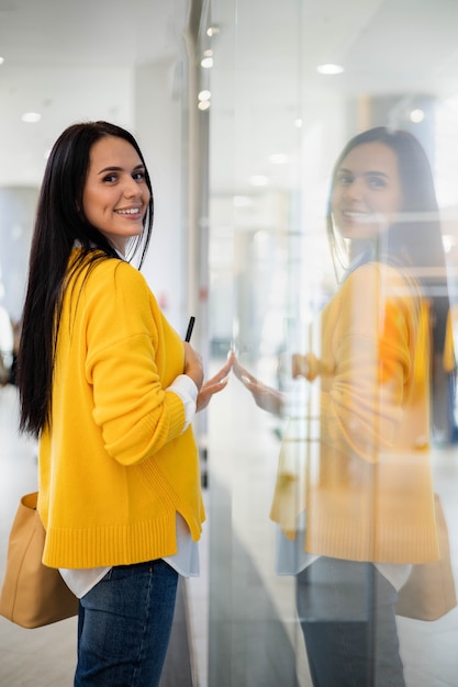 Photo beautiful female shopaholic looking at fashion boutique showcase holding paper shopping bags