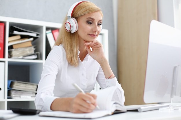 Beautiful female student with headphones listening to music and learning.