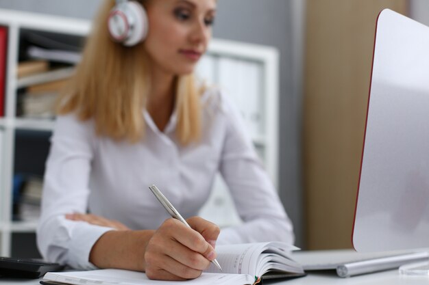 Beautiful female student with headphones writing