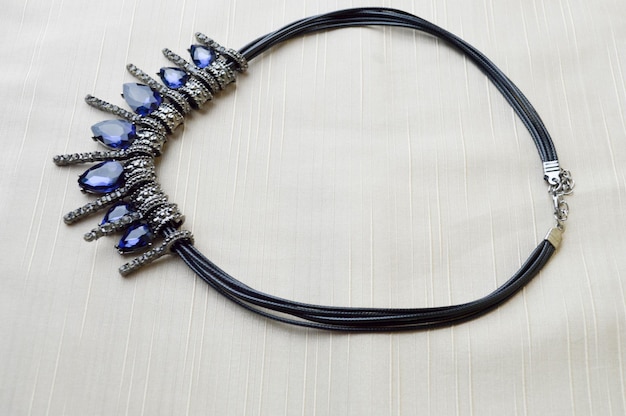 A beautiful feminine fashionable necklace on a black rubber band with blue shining gems diamonds