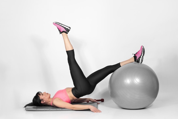 Beautiful fit woman in middle 40 doing exercises with Pilates ball studio shot