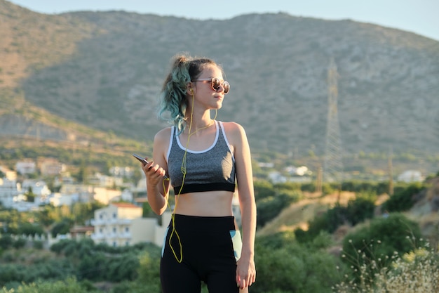 Beautiful fitness runner girl using smartphone and headphones