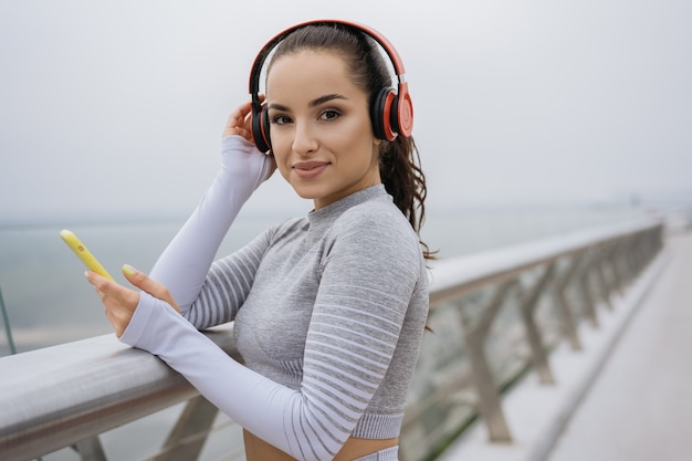 Beautiful fitness woman in sportswear listening to music on headphones.