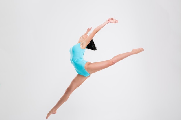 Beautiful flexible woman gymnast isolated on a white wall