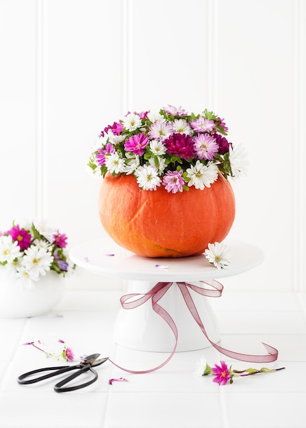 Beautiful florist arrangement with colorful aster flowers in a pumpkin vase