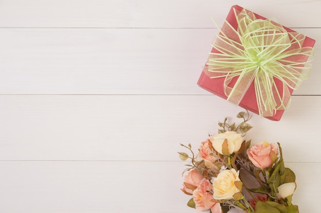 Beautiful flower and gift box on wooden background with romantic