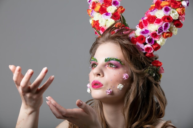 Beautiful flower girl with horns Goddess Flora Beautiful woman with fantastic makeup is blowing