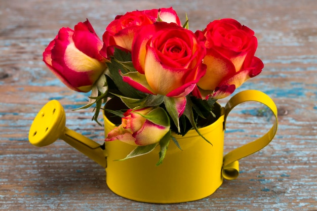 Beautiful flower in watering can on grunge wooden table.With copy space.