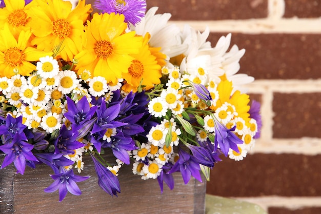 Beautiful flowers in crate on brick wall background