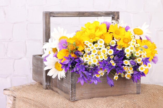 Beautiful flowers in crate on light background