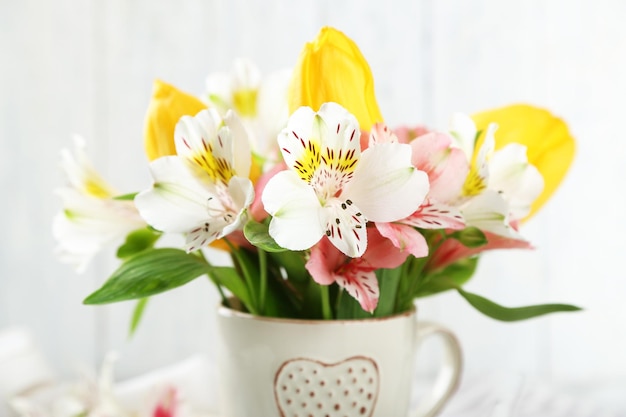 Beautiful flowers in cup on wooden background