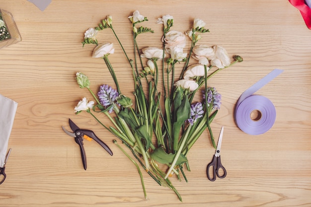 Beautiful flowers and florist equipment on wooden table