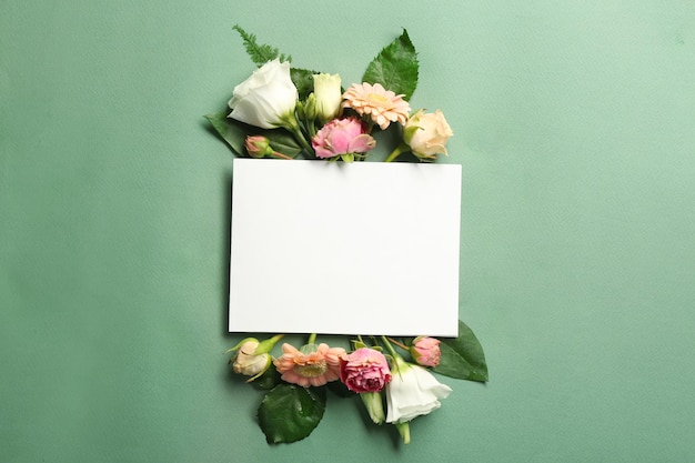 Beautiful flowers and green leaves as floral frame and paper card on color background