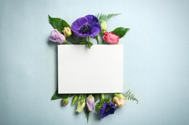 Beautiful flowers and green leaves as floral frame and paper card on light background