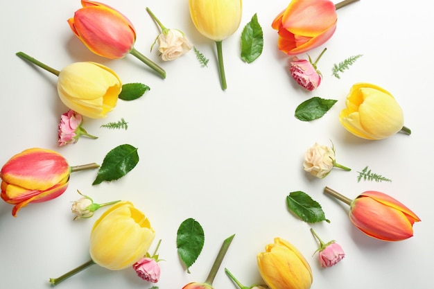 Beautiful flowers and green leaves as floral frame on white background