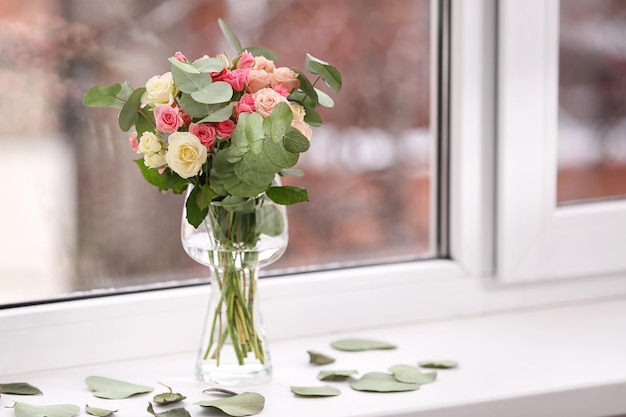 Beautiful flowers in vase on windowsill