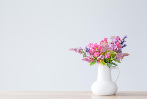 beautiful flowers in white jug on wooden shelf