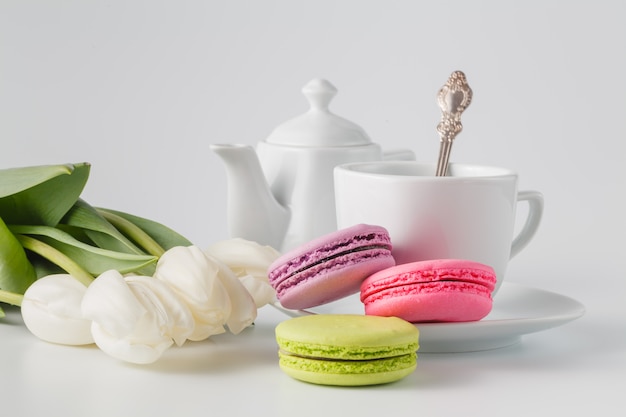 Beautiful flowers white tulips with colorful macaroons laid on a white platter on white surface