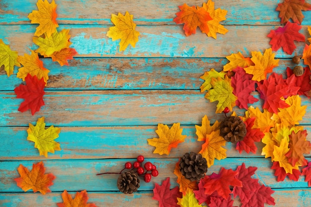 Beautiful frame composed of autumn maple leaves with pine cones wood plank