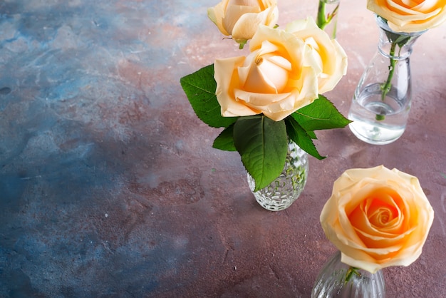 Beautiful fresh cut beige Roses in glass vase on stone background. 