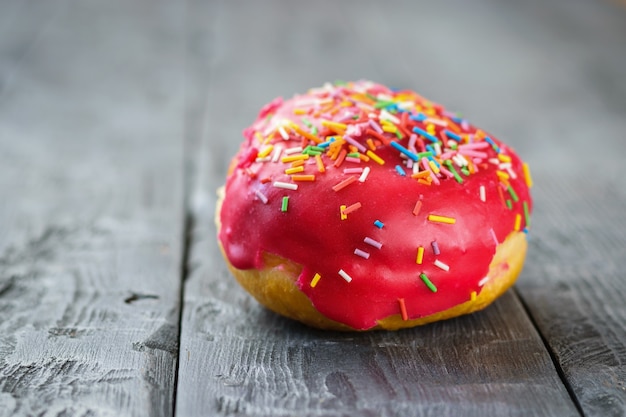 Beautiful fresh donut in red glaze on wooden table