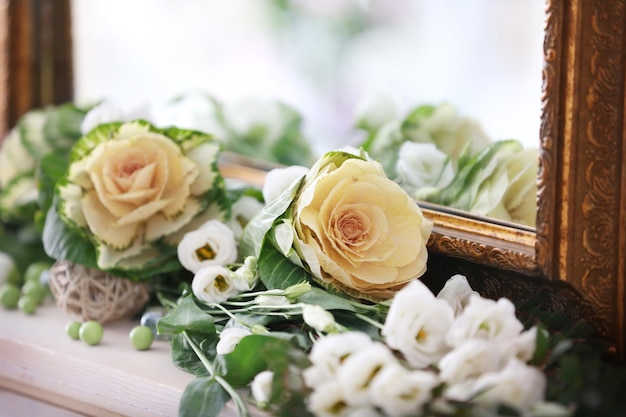 Beautiful fresh flowers lying near mirror closeup