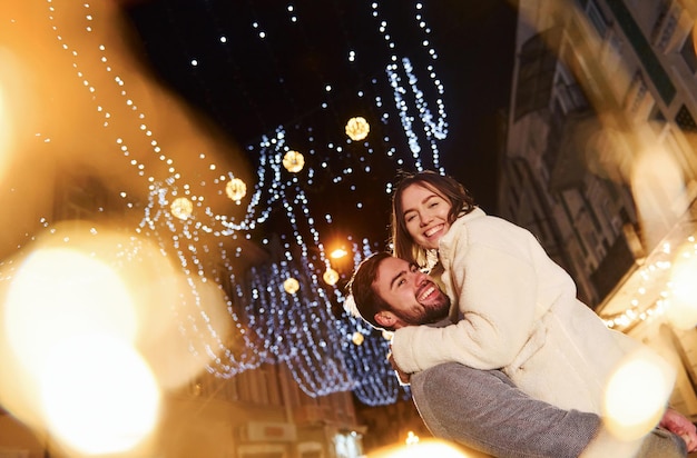 Beautiful garland lighting Happy young couple celebrating New year outdoors on the street