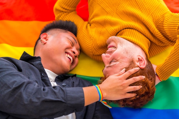 Beautiful gay couple being romantic at home over rainbow flag lgbt concept