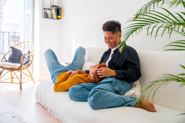 Beautiful gay couple being romantic on the sofa cuddling lgbt concept