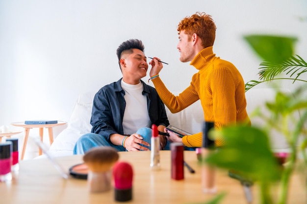 Beautiful gay couple doing makeup and having fun being romantic at home lgbt concept