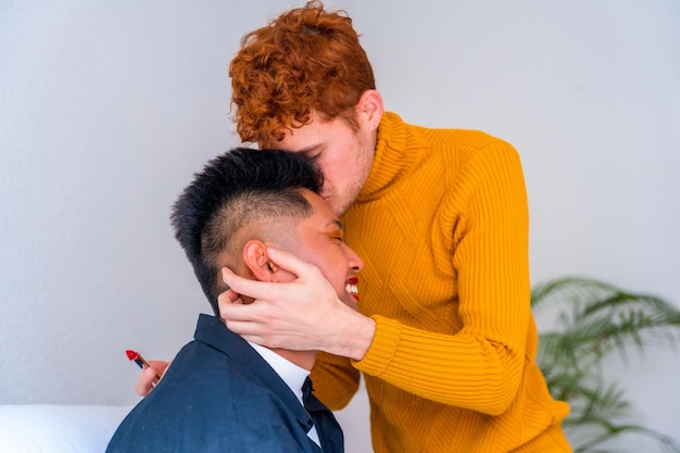 Beautiful gay couple doing makeup kiss being romantic indoors at home lgbt concept