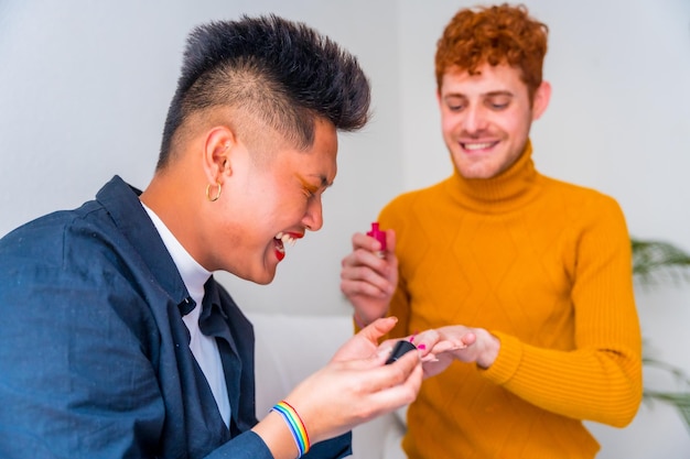 Beautiful gay couple doing makeup painting their nails and having fun indoors at home lgbt concept