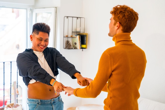 Beautiful gay couple having fun and dancing to music indoors at home lgbt concept